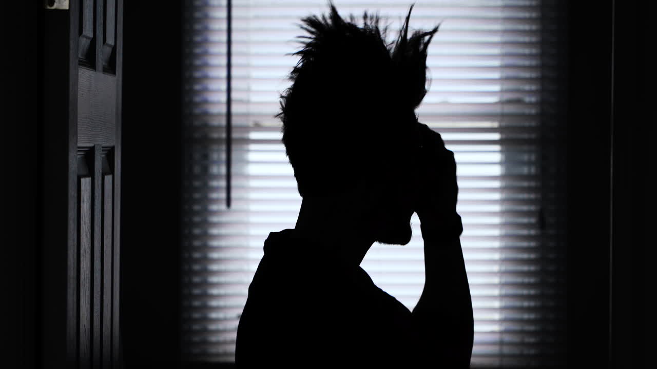 silueta de un joven rockero punk peinando su cabello largo en un mohawk con púas en 4k