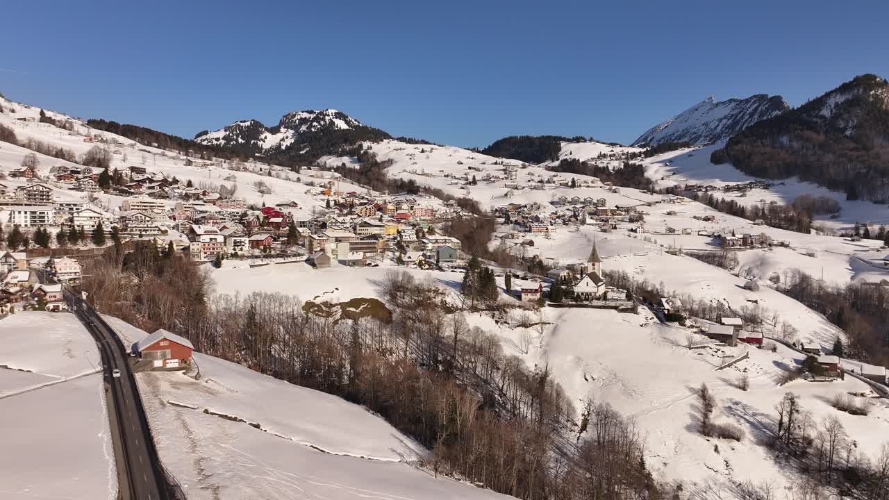 Snowy alpine village of Amden with mountain backdrop and clear blue sky Switzerland