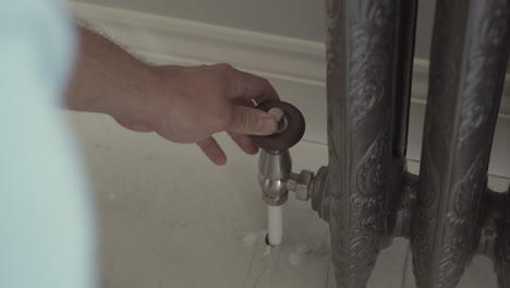 a plumber tightening a bolt on a radiator