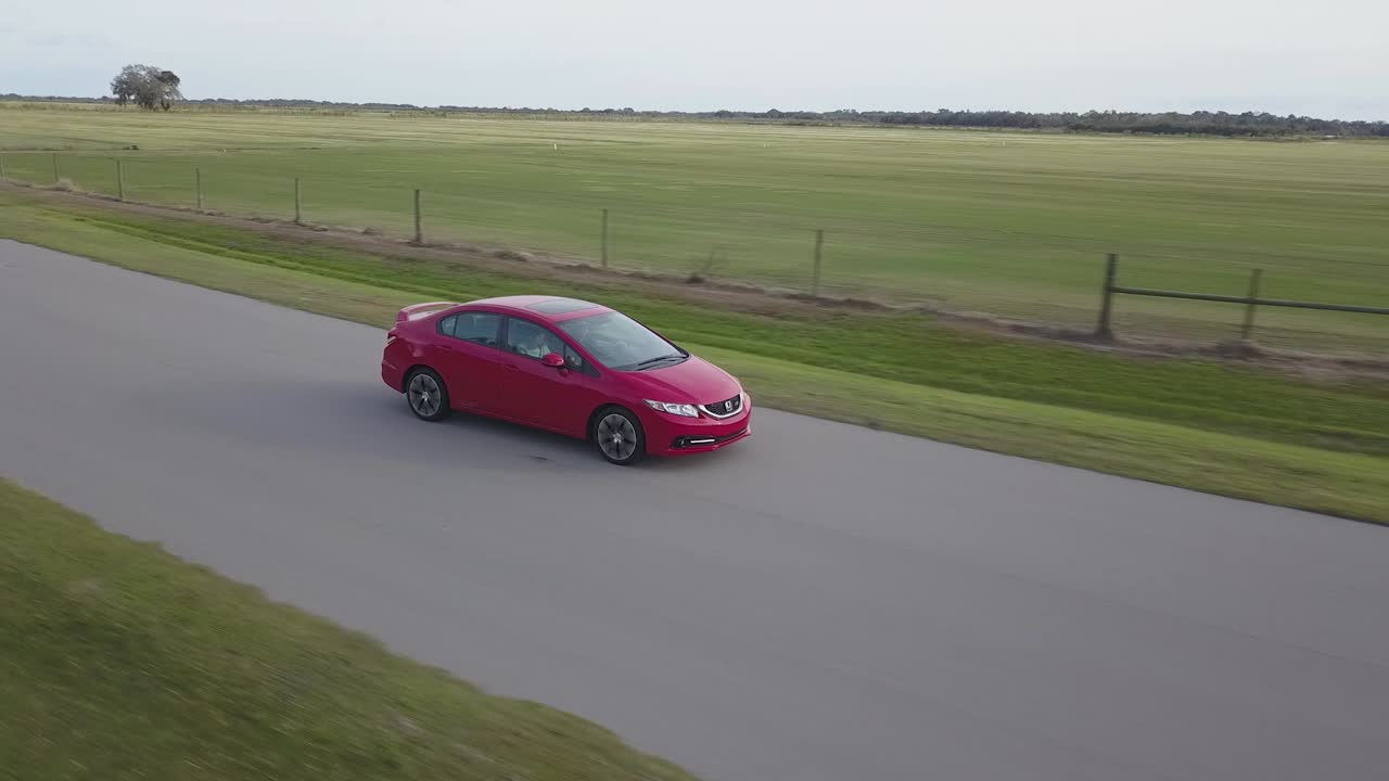 Aerial View of Red Sports Car Frontal View Driving Through Empty Country Road at Sunset