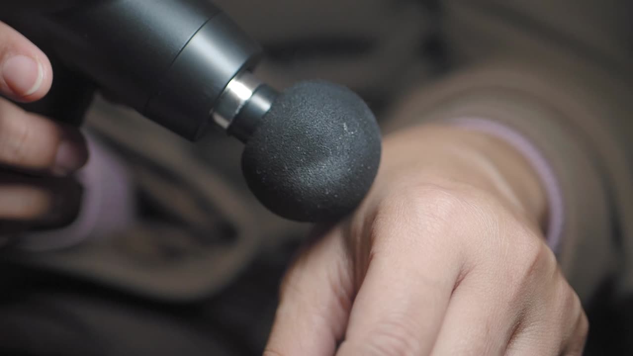 Close-up de Mão Recebendo Massagem Percussiva de uma Pistola de Massagem