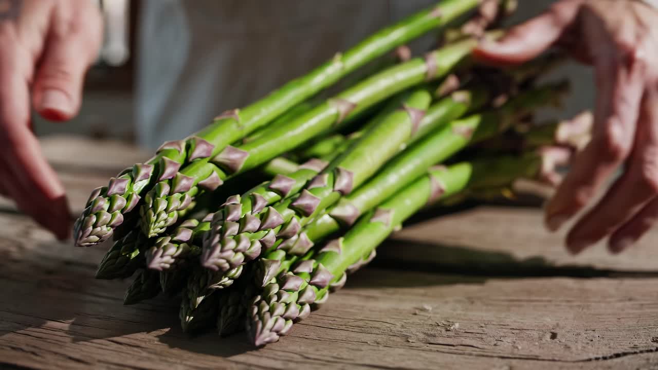 Close-up video shot of fresh asparagus on a rustic wooden table, captured from a low angle
