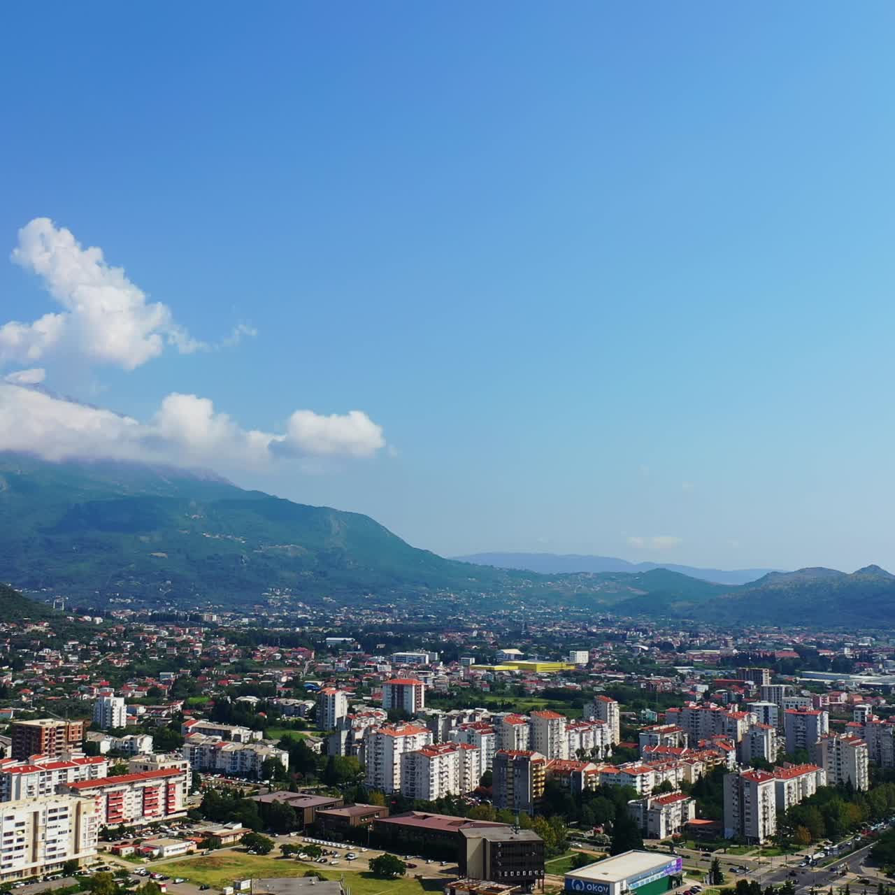 Lovely view of the sunny city that scattered among the mountains and the sea. Bar, Montenegro from aerial perspective