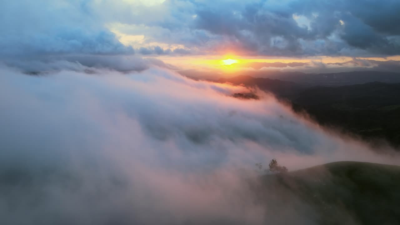 Volando attraverso nuvole e nebbia sopra una valle di montagna al tramonto, Drone aereo 4K