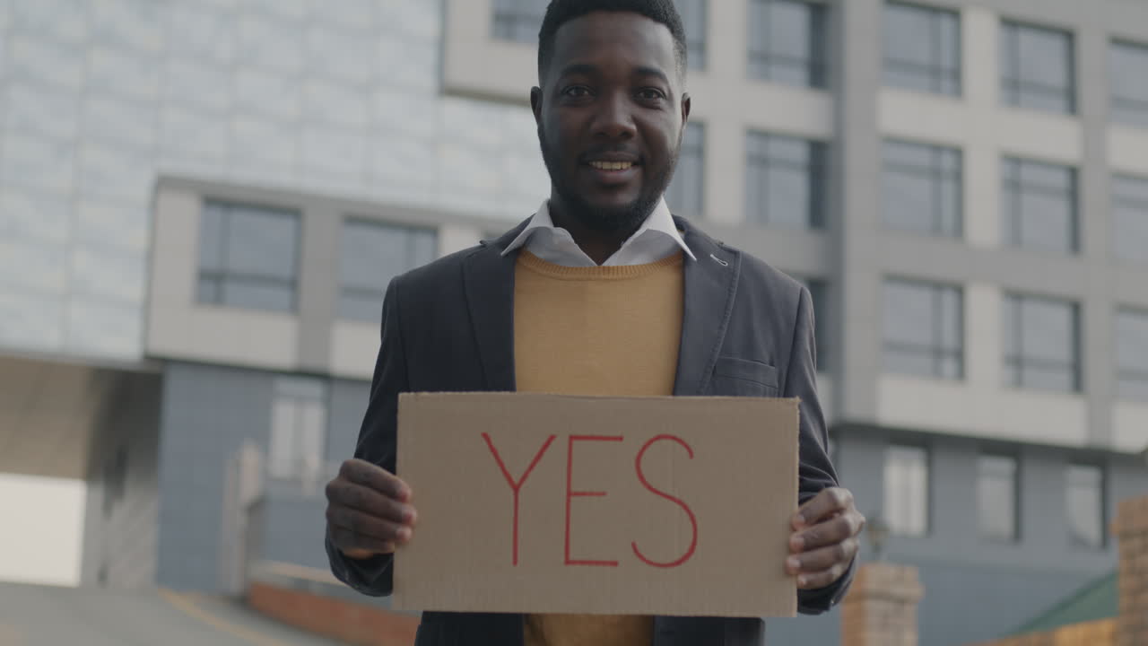 Man holding a cardboard sign with the word YES