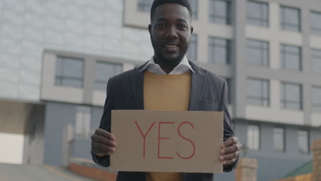 man holding a cardboard sign with the word yes