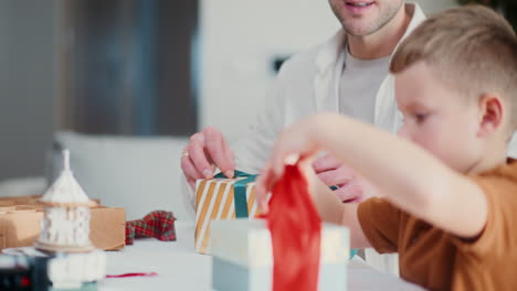 little boy wraps presents with ribbon