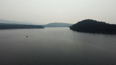 Crane-drone-shot-of-Lake-Payette-with-its-tree-filled-shore-and-boats-floating-along