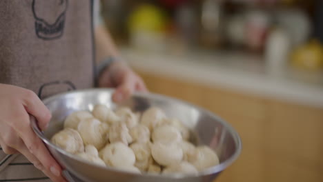 woman shaking fresh mushrooms in a metal bowl