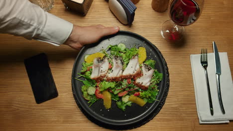 waiter putting plate dinner food on restaurant table. dining delicious concept.