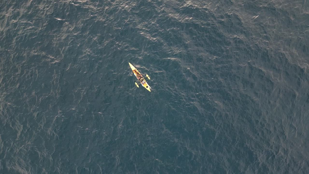un pescador en un kayak de pesca amarillo en medio del océano pacífico
