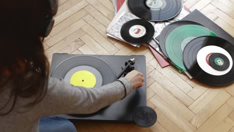 girl playing music on turntable at home.