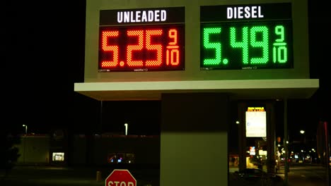 gas station prices led light up sign for regular and diesel fuel at night over 5 dollars per gallon credit and cash price, during 2021 2022 war time recession, ground up lonely shot desolate streets