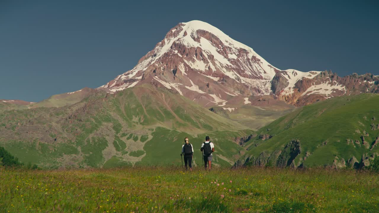 Hikers explore lush landscape near Kazbegi Mountain, Georgia