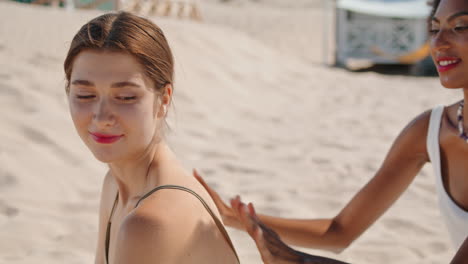 amigos aplicando crema para broncearse en la playa de cerca. amigas felices descansando en verano.
