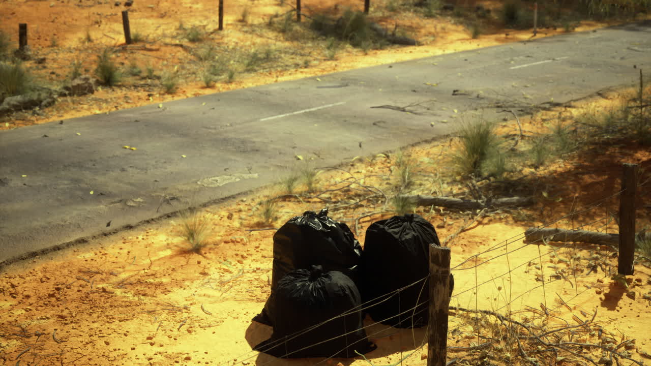 Trash bags left along a deserted road in the arid landscape of the countryside