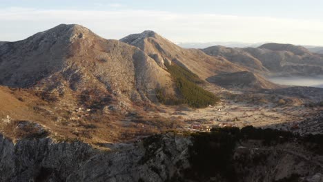 Aerial-view-of-vast-valley-surrounded-by-brown-mountains-and-cliffs