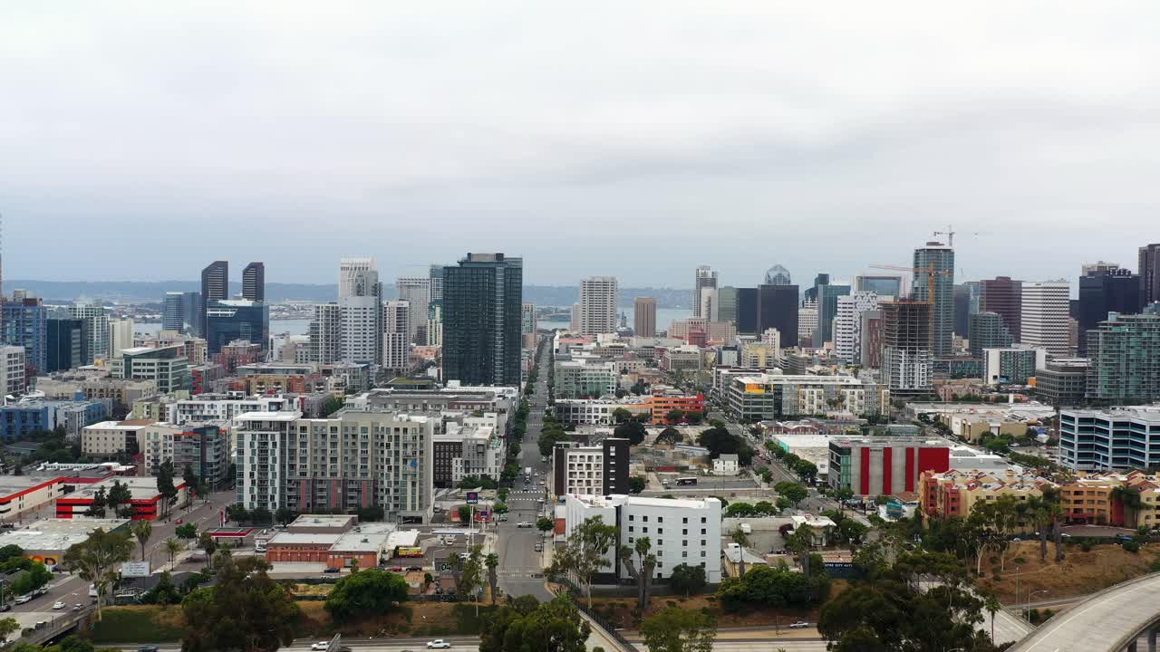 Drone voando em direção ao centro de San Diego com um bonde passando ao fundo durante o início da manhã.