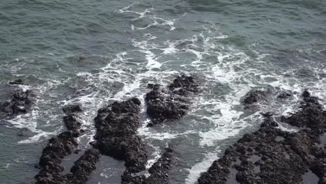 Las-Suaves-Olas-Del-Océano-Acarician-Con-Gracia-Las-Piedras-Negras-Esparcidas-En-Las-Tranquilas-Aguas