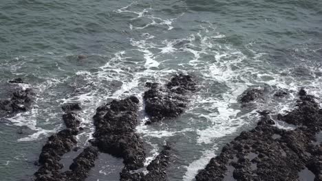 las suaves olas del océano acarician con gracia las piedras negras esparcidas en las aguas tranquilas