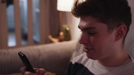 joven usando las redes sociales en un teléfono inteligente en un hogar acogedor