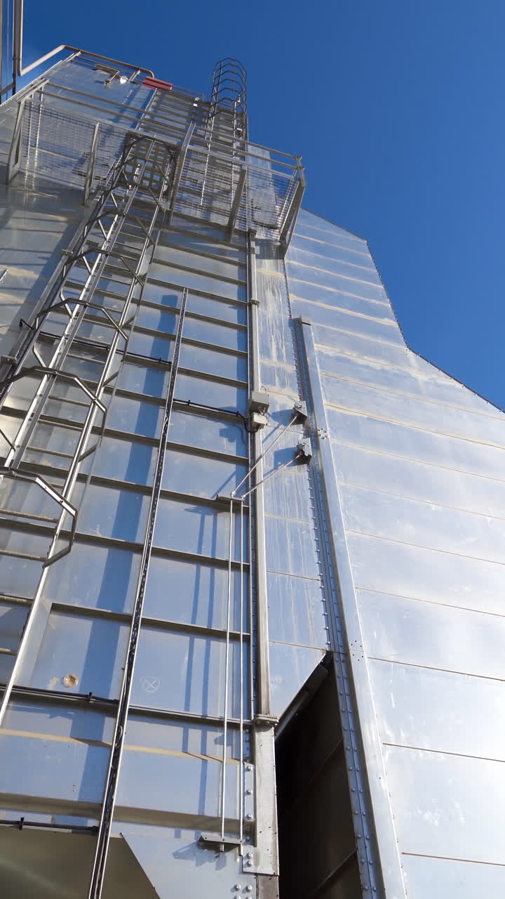 Industrial part of manufacture at sunlight. Modern industrial plant on blue sky background. Exterior of a new building for agribusiness. Vertical video