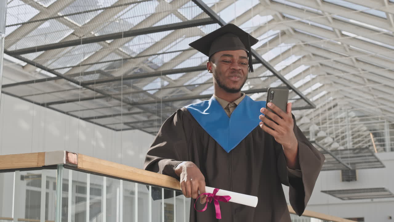 Portrait of Joyful Male African-American Graduate Having Video Call