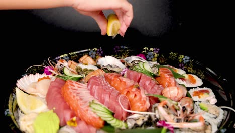 exprimir el limón con la mano sobre sushi variado