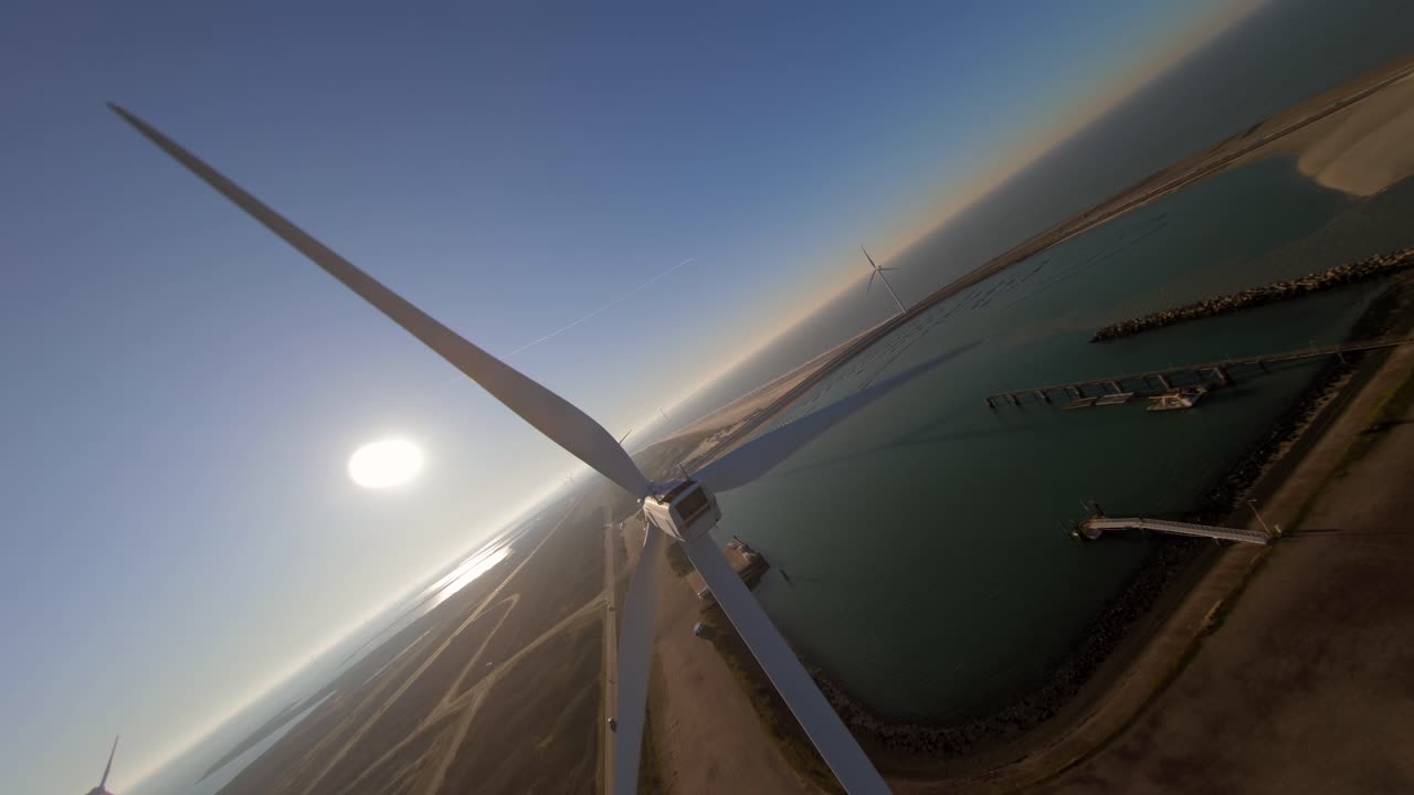 Low to high angle of a large windturbine on a dyke in the middle of the sea during sunset