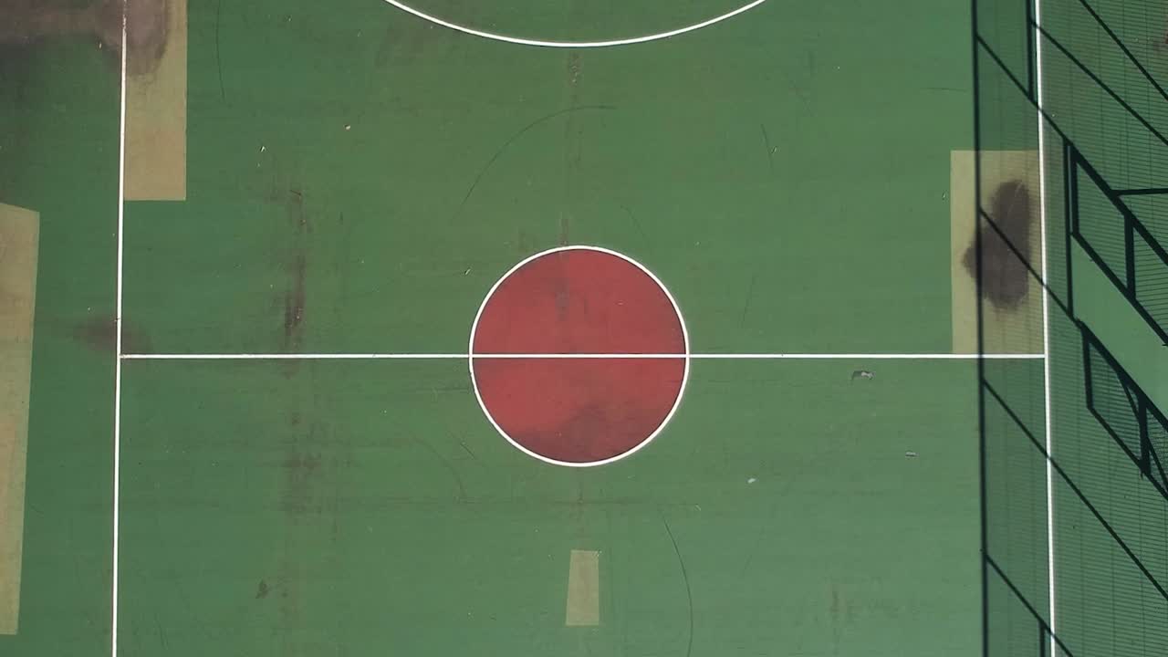 Ascending aerial overhead drone clip from the center of a basketball court in a sports complex in Choristi Village in Drama, Greece