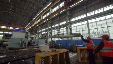 industrial workers handling large metal part in a factory