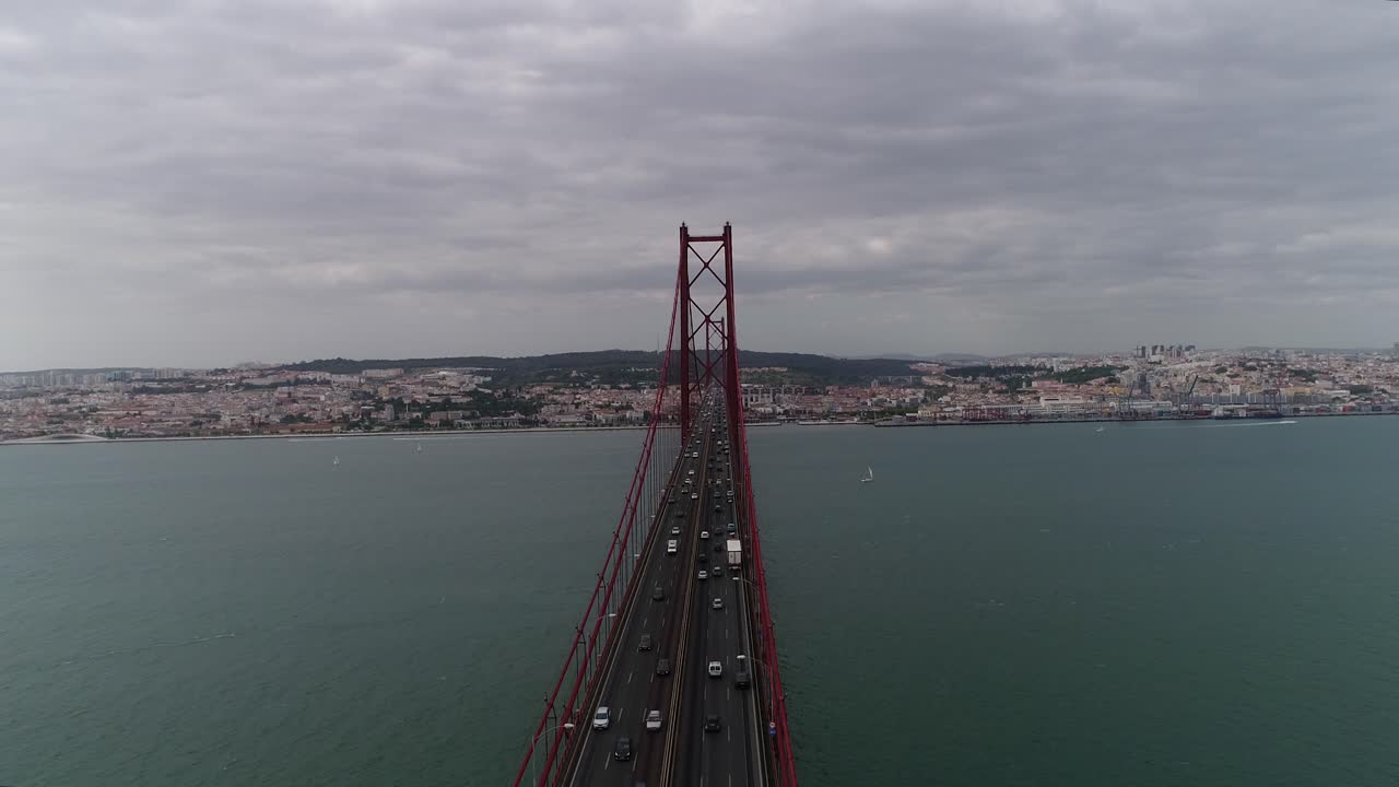 Vista aerea ravvicinata di auto che transitano sul ponte sospeso 25 de Abril di Lisbona al tramonto, Portogallo.
