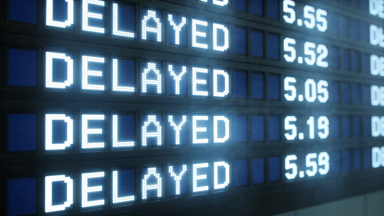 Panel de visualización de salidas actualizándose en aeropuerto, columna numérica actualizándose para indicar retrasos en vuelos.