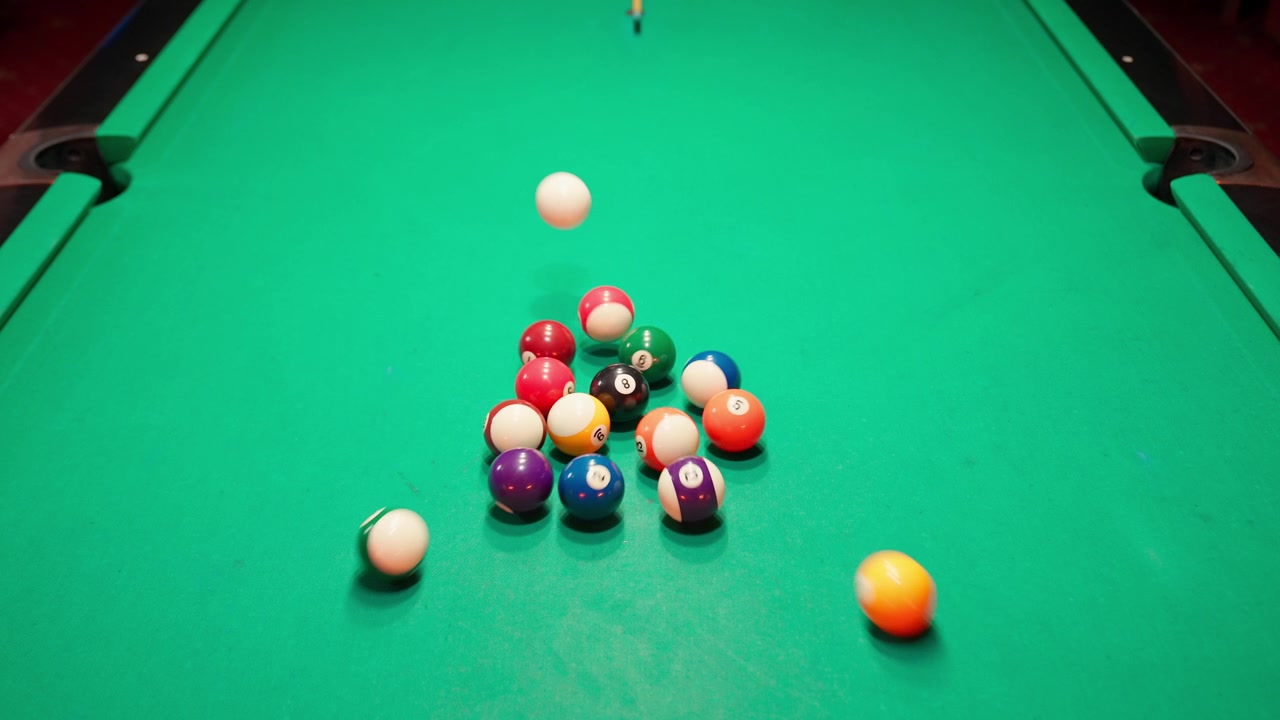 Cue Ball Breaking a Rack of Pool Balls on a Green Table