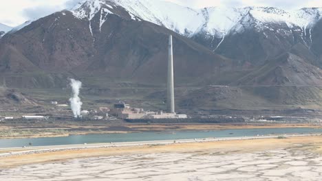 Aerial-upward-wide-view-of-large-copper-mine-smelter-stack-and-mountains-near-Salt-Lake-City,-Utah