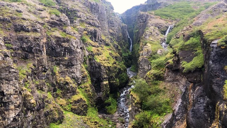 Paesaggio del canyon della cascata di Glymur con colombe che vi volano sopra