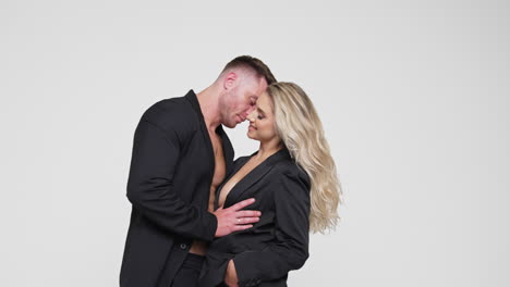 man stands close to a beautiful woman. loving man kisses and strokes his wife. white backdrop.