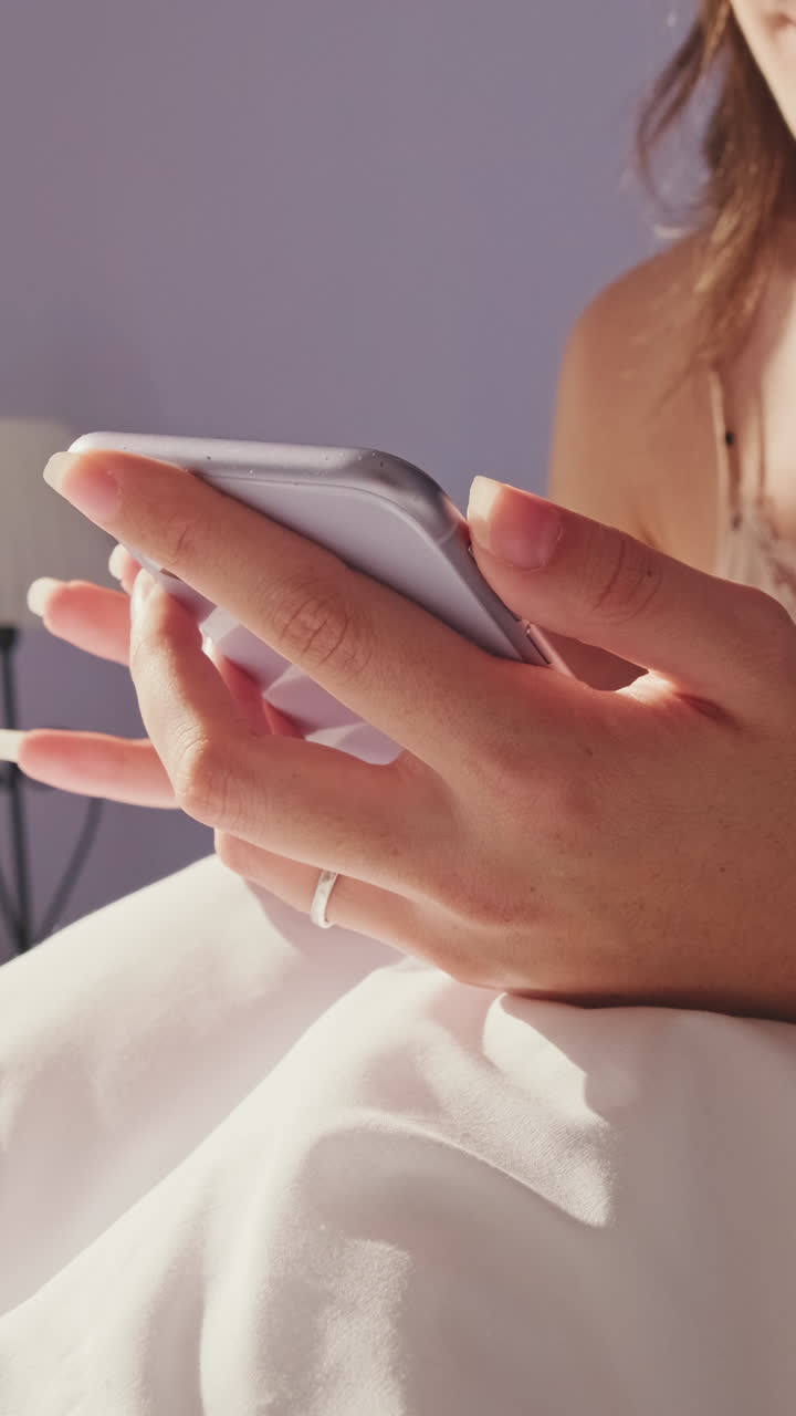 Donna che usa lo smartphone a letto