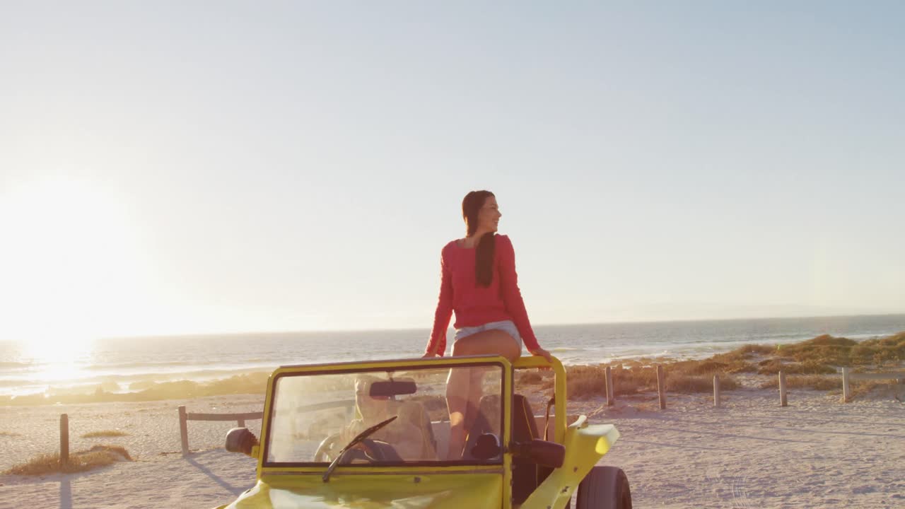 feliz pareja caucásica sentada en un buggy de playa junto al mar hablando