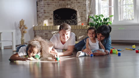 happy married couple play with their son with toys on the floor in living room