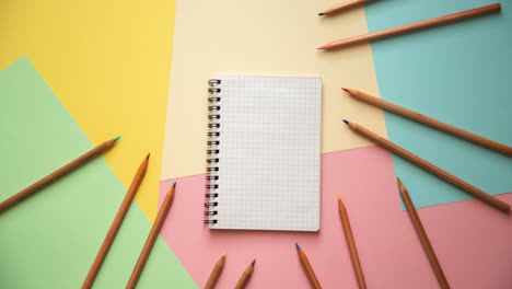 stop motion of a notebook and wooden pencils on pastel colored paper