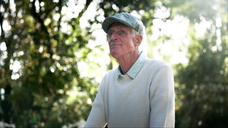 portrait of a senior man in a flat cap looking up outdoors