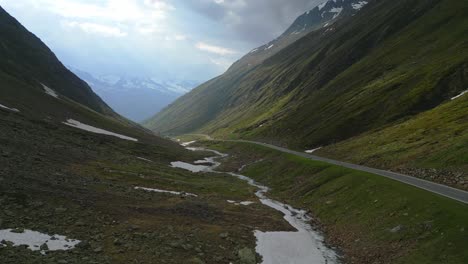 Cinematic-drone-shot-of-a-single-car-through-a-mountain-road-in-the-alps