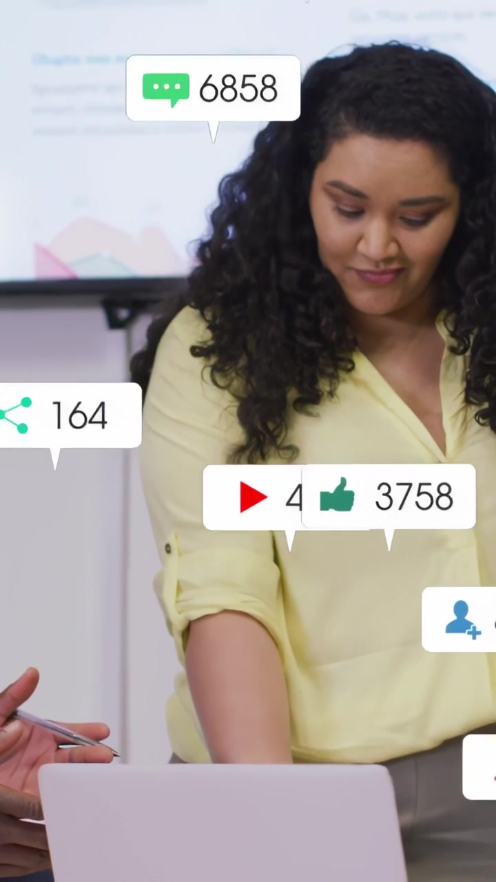 Vertical video: Woman tapping laptop, causing animated bubbles rising and updating media metrics