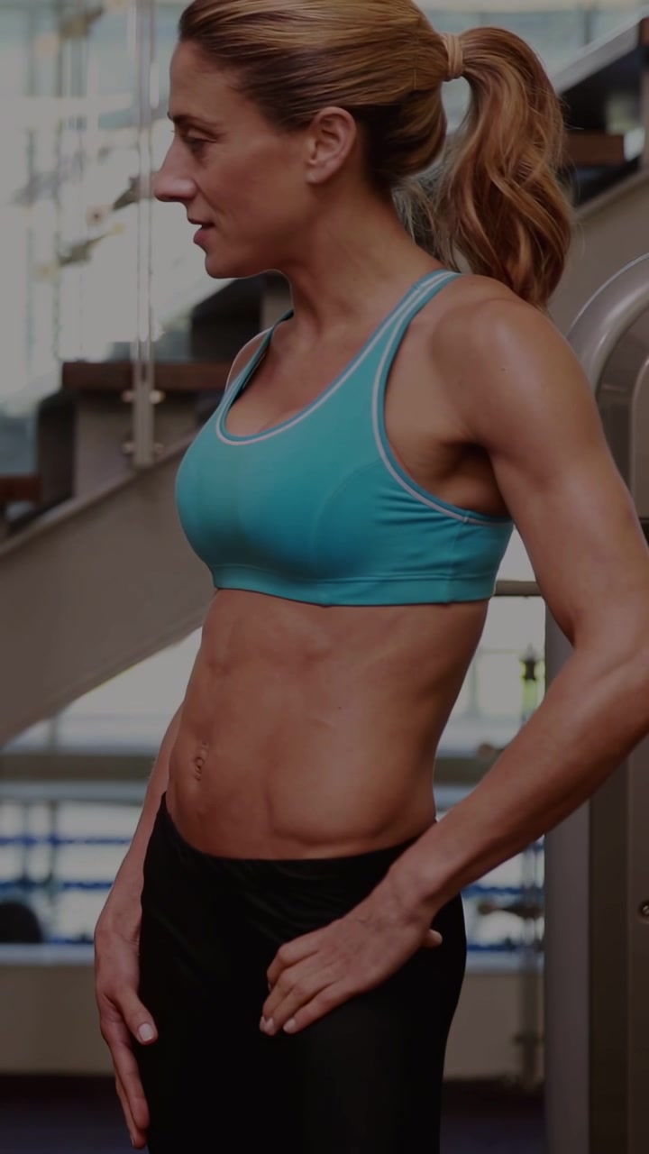 Video verticale: Donna istruttrice che tiene un attrezzo a cavo con codice a metà che si sovrappone al busto, mostrando dati di fitness.
