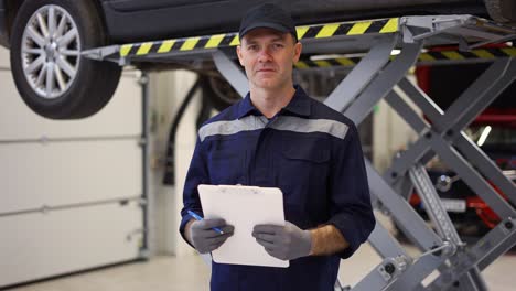 hombre en uniforme en un tiro de reparación de automóviles de pie con tableta ic servicio de automóviles