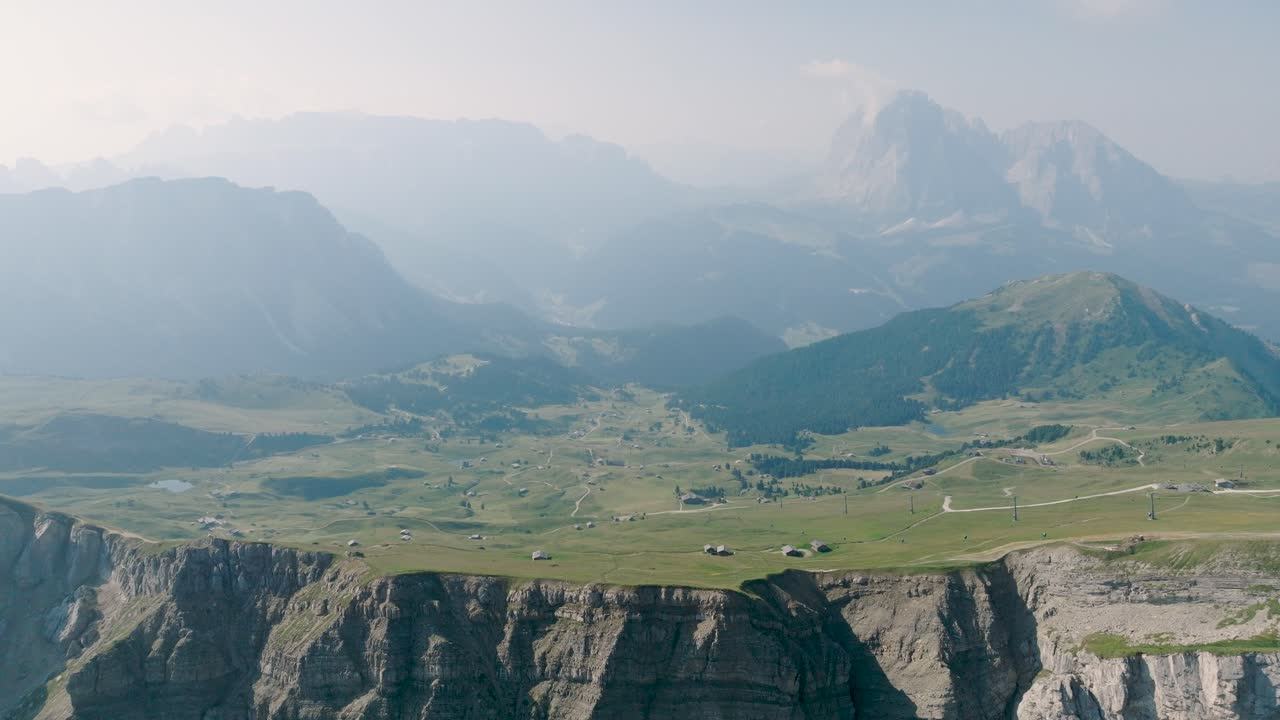el vuelo de drones muestra los verdes prados de montaña con un pequeño pueblo en un plano plano en los dolomitas en el tirol del sur
