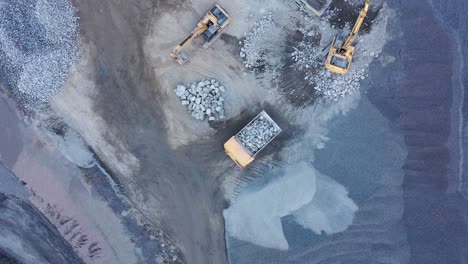 Drone-shot-of-mining-truck-dumping-rocks-near-mining-excavator