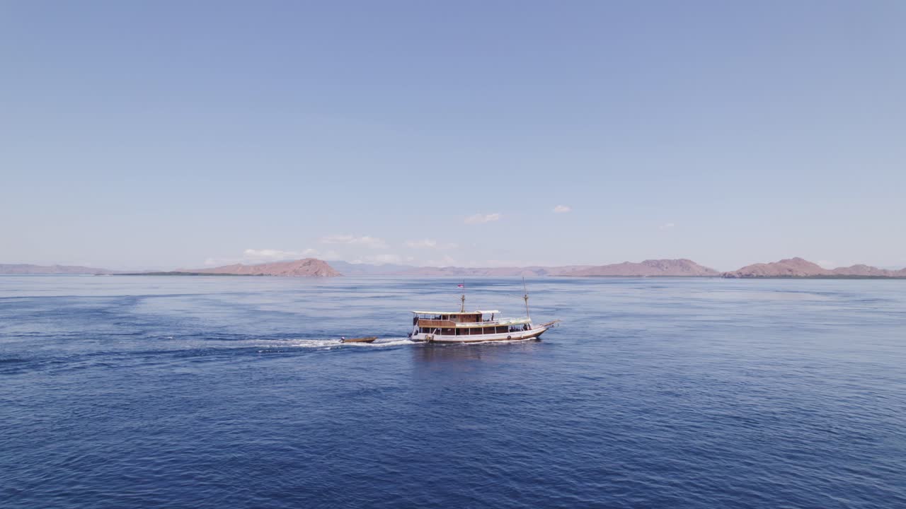 코모도 섬 먼 공중 궤도 근처의 푸른 바다를 여행하는 관광 유람선