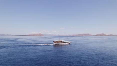 barco de crucero turístico que viaja en el océano azul cerca de la isla de komodo en órbita aérea distante